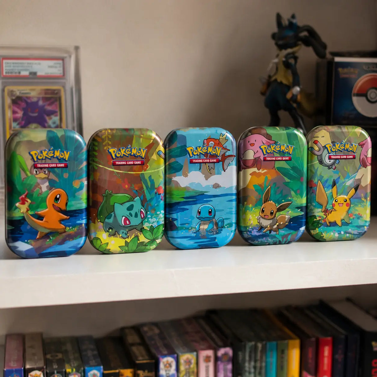 Alle 5 Pokemon Kanto Friends Mini Tins auf einem Sammlregal mit PSA-Karte und Pokemon-Figuren