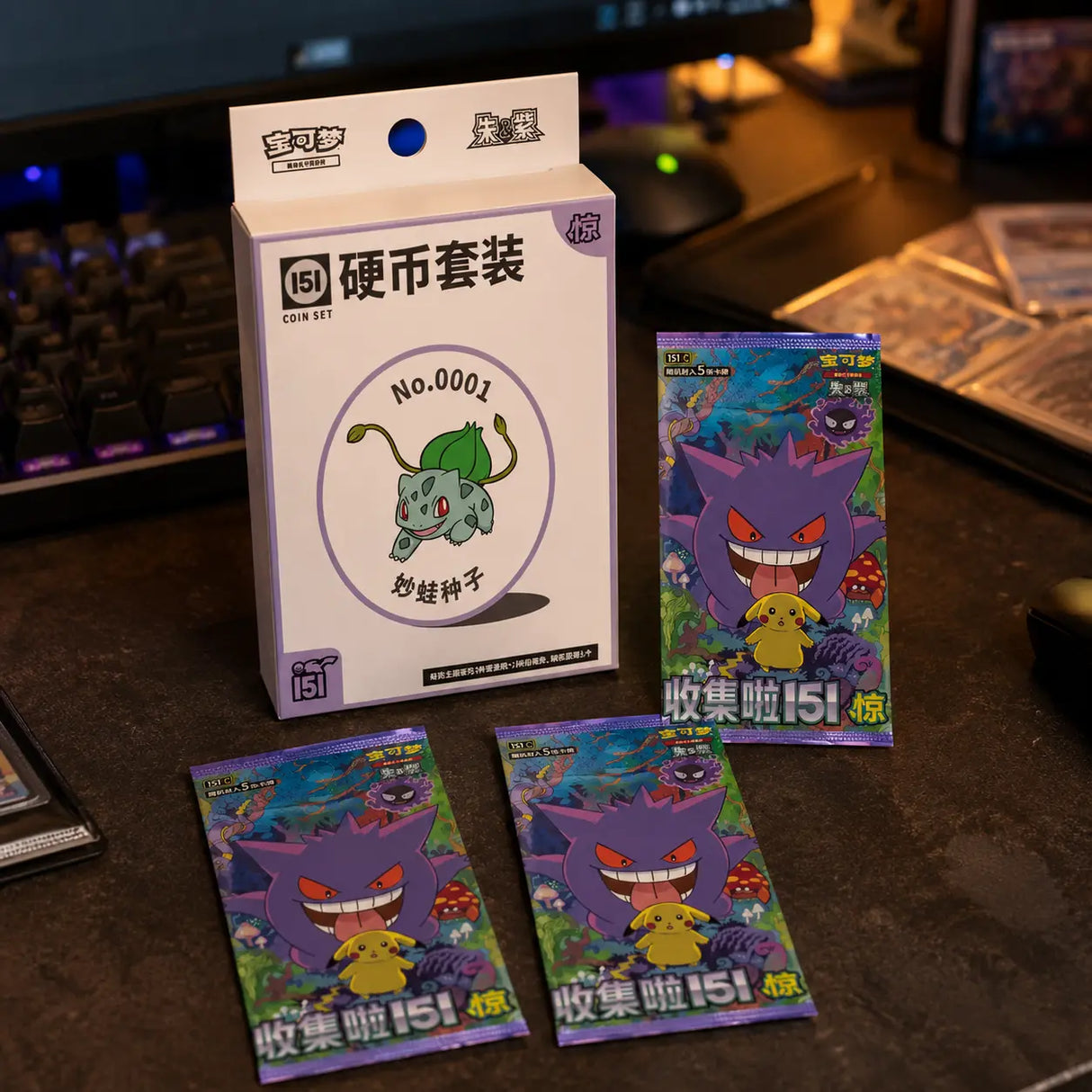 Pokemon 151 Surprise Coin Set auf Gaming-Tisch – Box mit Bulbasaur Artwork und drei 151 Surprise Booster Packs